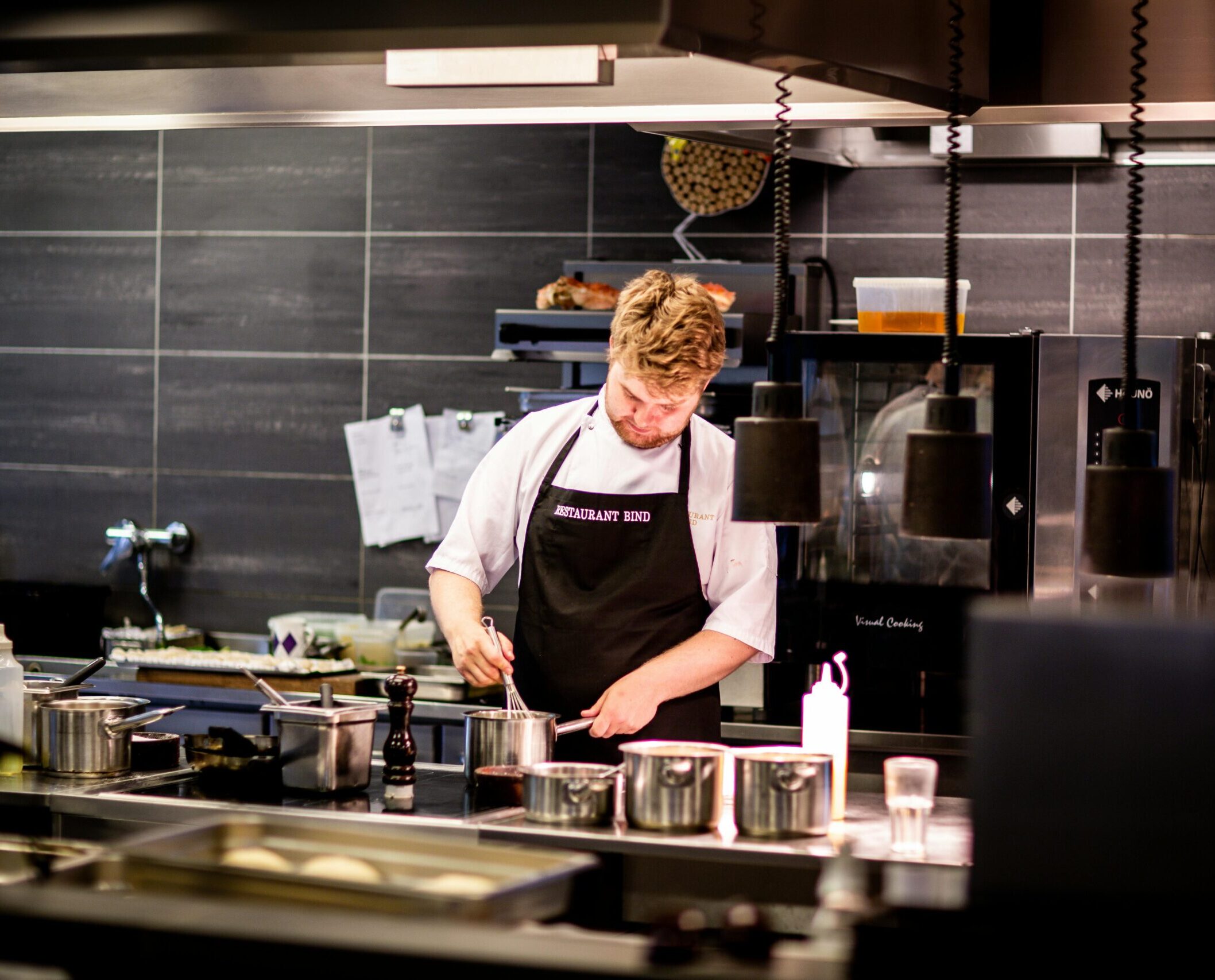 Chef preparing meal in a modern kitchen with various cookware.