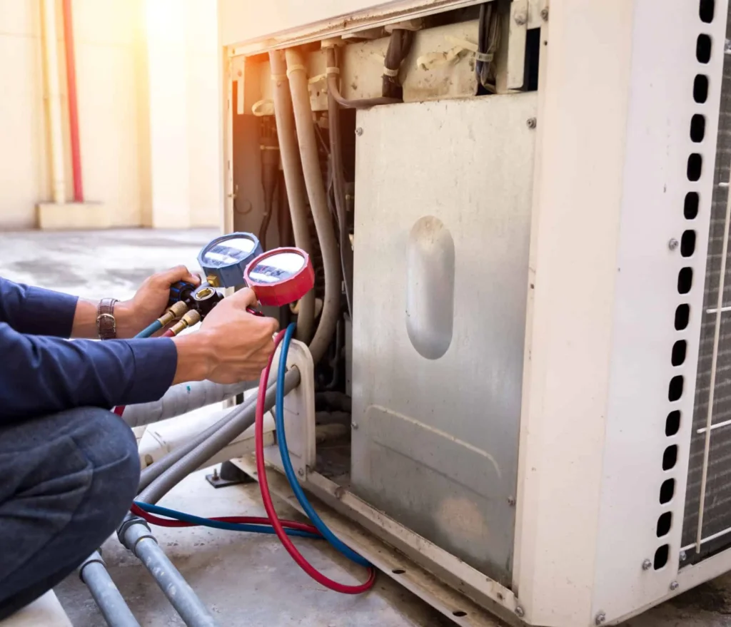 Technician using HVAC gauges to check refrigerant levels on a heat pump outdoor unit during repair service in Spokane, WA