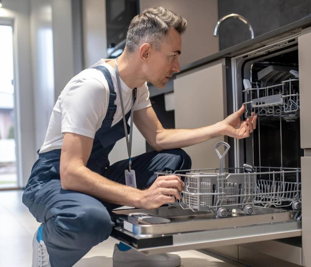 technician inspecting open dishwasher and checking upper rack mechanism